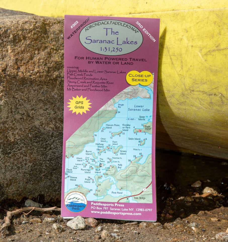 The Saranac Lakes paddlers map leaning against a rock and yellow kayak