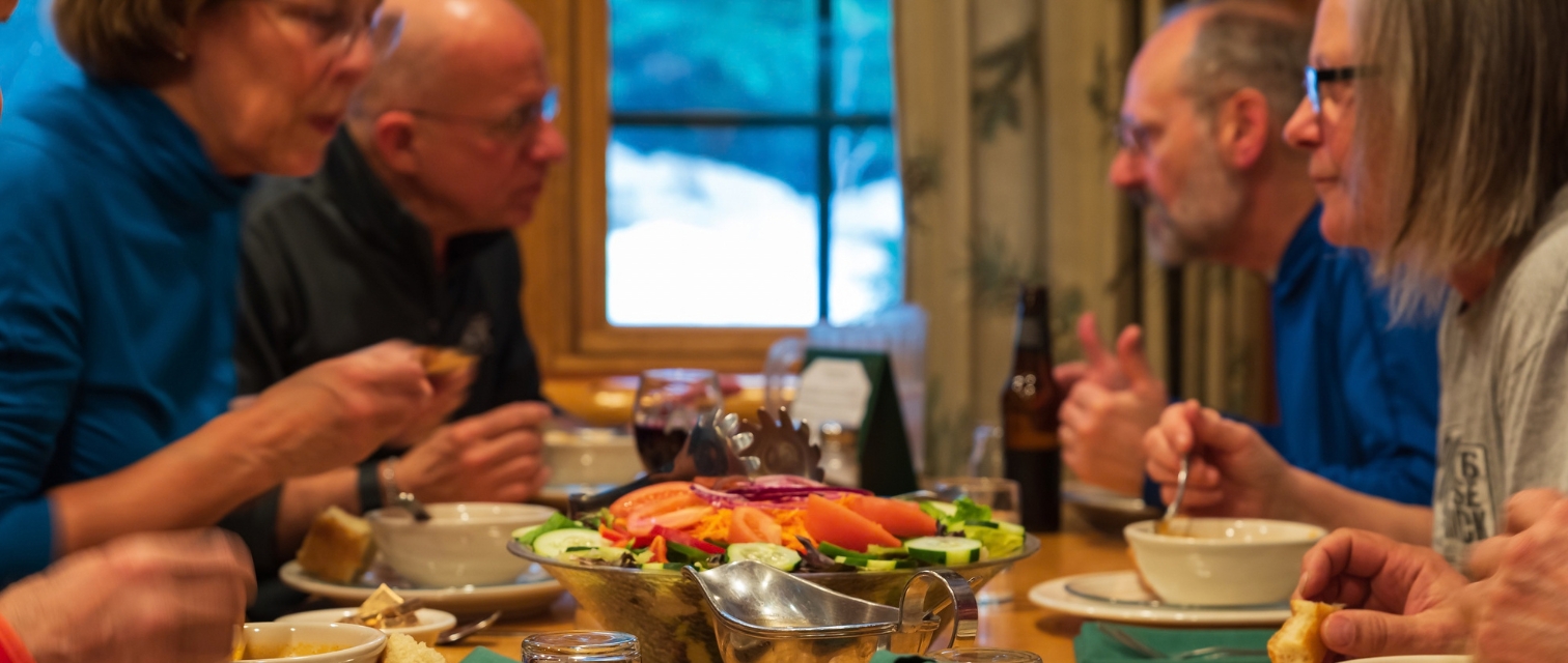 a group of people sitting at a dinner table having a conversation