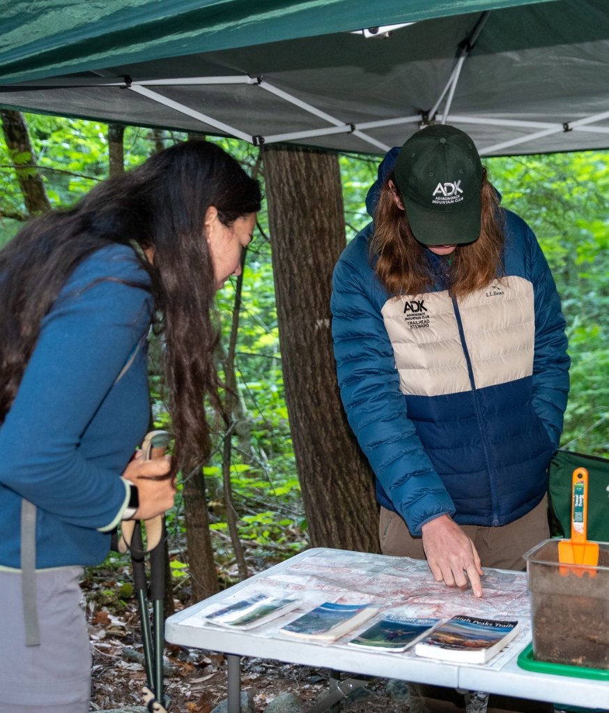 route 73 trailhead steward points at map while talking to hiker