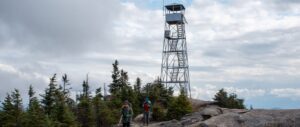 two hikers at the summit of hurricane mountain on a mostly cloudy day