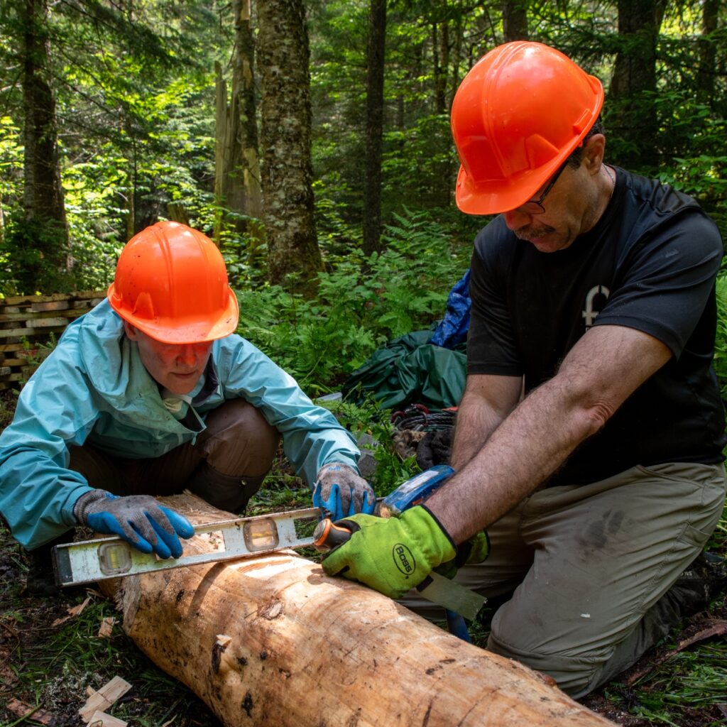 two people doing trail work and wearing orange hard hats