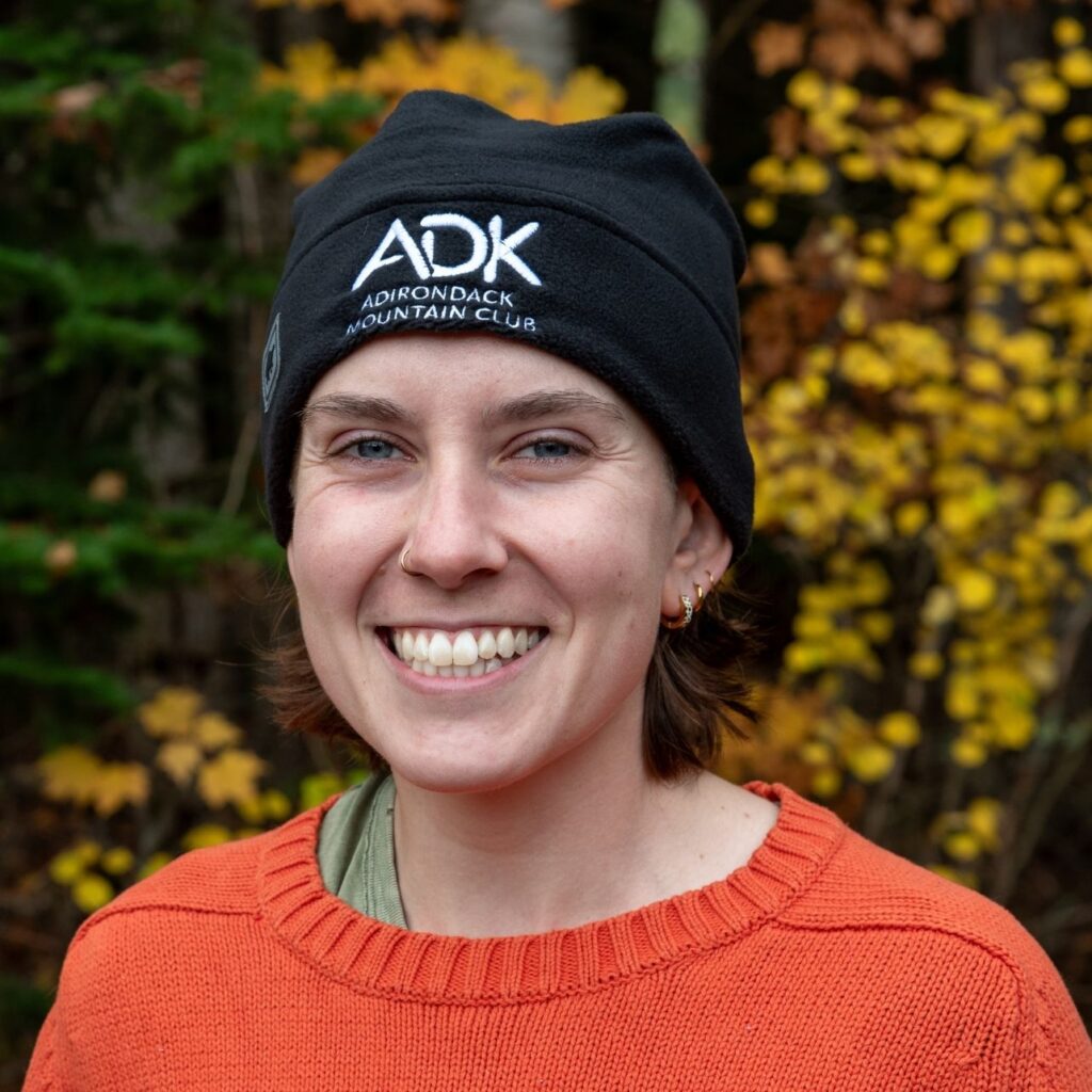 woman in an orange sweater wearing a black Adirondack Mountain Club hat