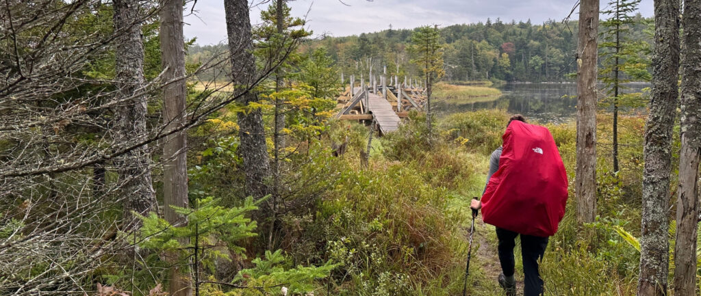 hiker with a large pack and a red rain cover on the northville placid trail