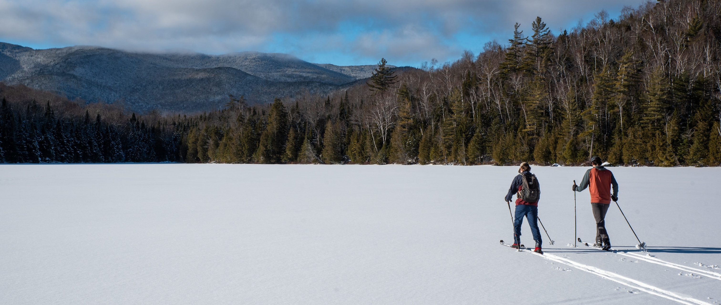 two people cross-country skiing across a frozen lake in the adirondacks